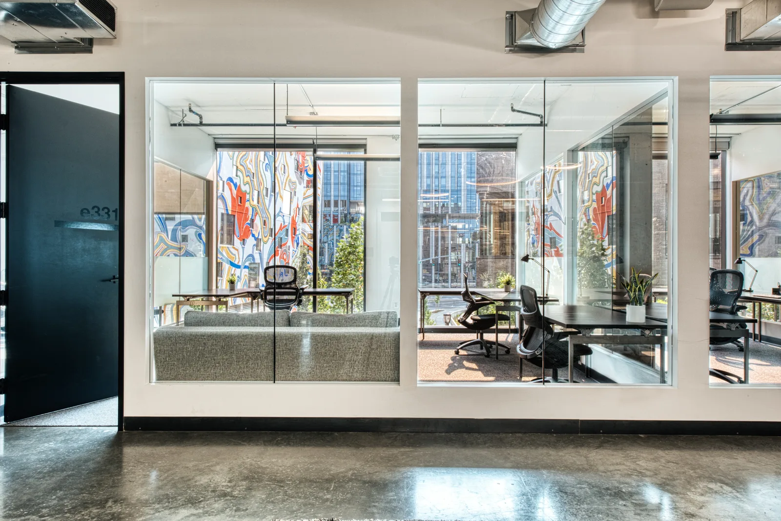 A glass-walled private office facing the mural at CENTRL Eastside.